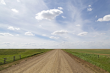 Clouds and blue sky over a dirt track in the Badlands of Alberta, near Drumheller, Alberta, Canada, North America