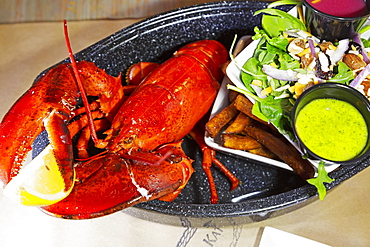 A lobster dinner served with salad, sauces and French fries in Barrington, Nova Scotia, Canada, North America