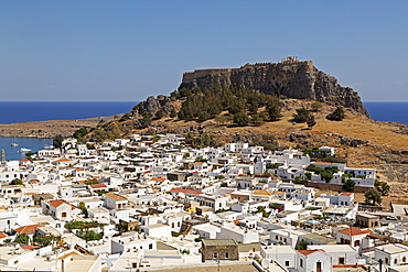 The Lindian Acropolis, site rises over white houses in the fishing village of Lindos on Rhodes, Dodecanese, Greek Islands, Greece, Europe