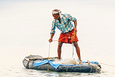 Fisherman retrieving net on small raft offshore of popular Marari Beach, Mararikulam, Alappuzha (Alleppey), Kerala, India, Asia