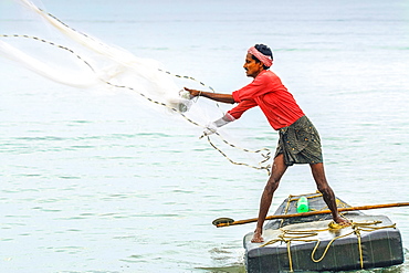 Fisherman casting weighted net on small raft offshore of popular Marari Beach, Mararikulam, Alappuzha (Alleppey), Kerala, India, Asia