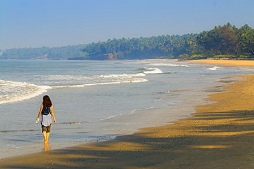 Lone traveller on lovely palm-fringed, Kizhunna Beach, south of Kannur on Kerala's north coast, Kizhunna, Kannur, Kerala, India, Asia