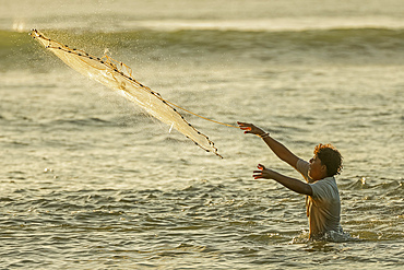 Man casting a weighted throw net at Nosara Boca (river mouth), a popular fishing spot for locals. Boca Nosara, Nosara Beach, Guanacaste, Costa Rica