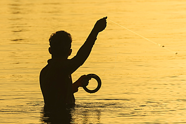 Local man handline fishing at the mangrove fringed Nosara Boca (river mouth) and estuary at sunset. Nosara River, Boca Nosara, Guanacaste, Costa Rica