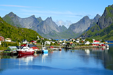 Mountains ships and houses reflect in the fjord Reine Moskenesoya Lofoten Norway