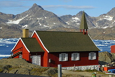 Red church at fjord and mountain chain Ammassalik Eastgreenland