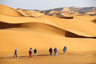 Tourists hike through sanddunes in the desert Mandara Libya