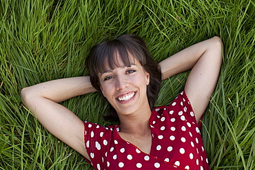 Young woman, 25, lying in a meadow