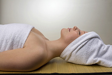 Young woman relaxing in a spa, towel wrapped around her head