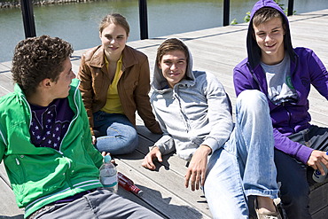 Three boys and a girl sitting on the floor, relaxing in the sun