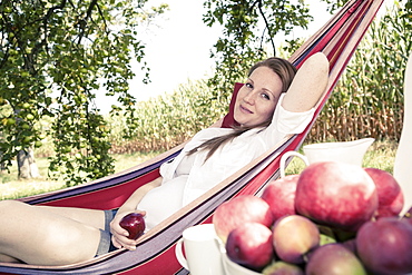 Pregnant woman in a hammock in the apple garden