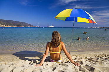 Woman sitting on the beach of Marina di Campo, Island of Elba, Tuscany, Italy, Mediterranean Sea, Europe