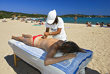 Chinese girl giving massage on the beach, Sardinia