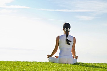 Young woman practising Hatha yoga, here the pose padmasana, lotus pose