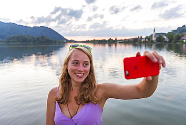 Young woman taking selfie and smiling, Schliersee, Upper Bavaria, Bavaria, Germany, Europe