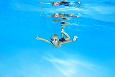 Little boy with swimming goggles, learning to swim underwater in the pool, Ukraine, Europe