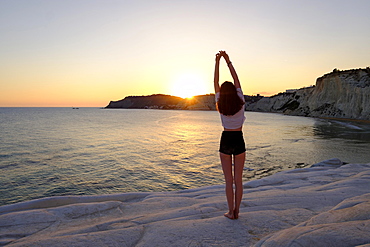 Young woman during sunset, rocky coast of Scala dei Turchi, limestone rocks, Realmonte, Province of Agrigento, Sicily, Italy, Europe