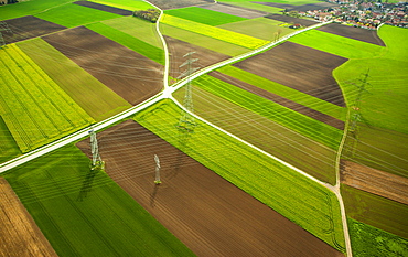 High-voltage transmission lines over farm fields in spring, aerial view, in Moosinning, Upper Bavaria, Bavaria, Germany, Europe