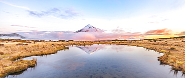 Reflection in Pouakai  Tarn lake, pink clouds around stratovolcano Mount Taranaki or Mount Egmont at sunset, Egmont National Park, Taranaki, New Zealand, Oceania