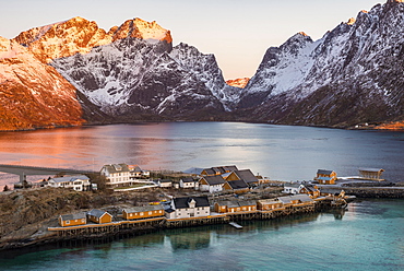 Rorbuer fishermen's huts on the island, at back sun lit mountains, Sakrisøya, Reine, Lofoten, Norway, Europe