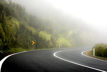 Curvy street in the fog with mossy mountain slope, Ponta Delgada, Flores Island, Azores, Portugal, Europe