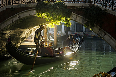 Canal, gondola with gondolier travels under a bridge, Venice, Veneto, Italy, Europe