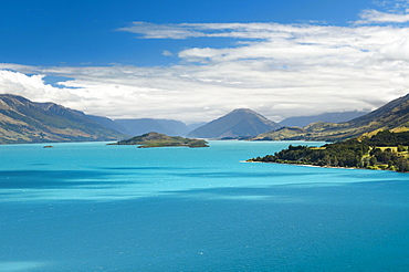 Blue sky with clouds over turquoise lake, Lake Wakatipu, Pig Island behind, near Queenstown, New Zealand, Oceania