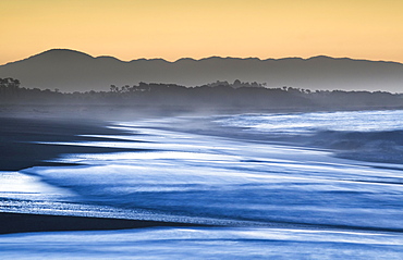 Surf with haze on a wide beach in the evening light, sunset in Haast, West Coast, South Island, New Zealand, Oceania