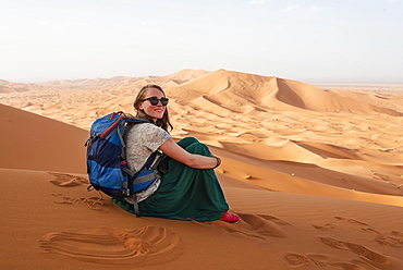 Female hiker on a red sand dune in the desert, dune landscape Erg Chebbi, Merzouga, Sahara, Morocco, Africa