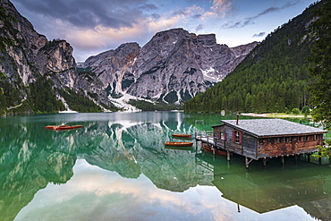 Green mountain lake with boats and boathouse, Seekogel peak in the back, water reflection, Lake Prags, Dolomites, Italy, Europe