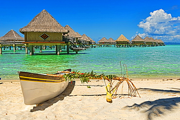 Polynesian outrigger canoe in front of pile bungalow complex, South Pacific, Bora Bora, French Polynesia, Oceania