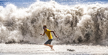 Young man with sunglasses running from a high wave, La Palma, Canary Islands, Spain, Europe