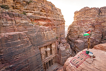 View from above into the gorge Siq, Pharaoh's treasure house carved into rock, facade of the treasure house Al-Khazneh, Khazne Faraun, mausoleum in the Nabataean city Petra with Jordanian flag, near Wadi Musa, Jordan, Asia