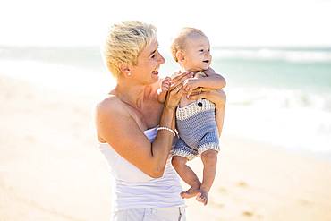 Attractive blond mother with 4 months old baby boy on the beach, Portugal, Europe