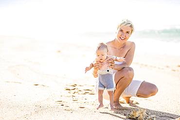 Attractive blond mother with 4 months old baby boy on the beach, Portugal, Europe