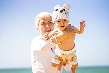 Happy blond mother with 4 months old baby boy on the beach, Portugal, Europe