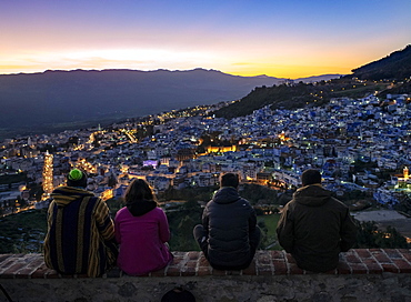 People sitting on a wall overlooking city Chefchauoen, sunset, Chaouen, reef mountains, Tangier-Tetouan, Morocco, Africa