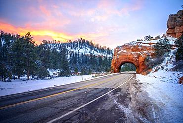 Road with tunnel through red rock arch in snow, at sunset, Highway 12, sandstone rocks, Red Canyon, Panguitch, Utah, USA, North America