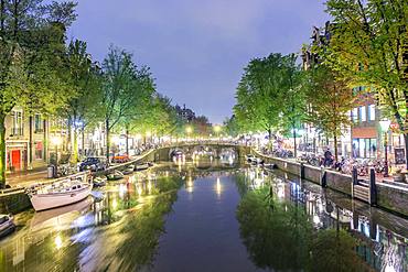 Canal with boats, bicycles on the street at night, Amsterdam, Holland, Netherlands