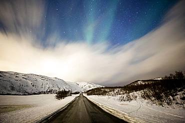 Northern lights over road with snow mountains, near Tromsoe, Troms, Norway, Europe