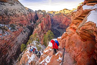 Young woman hikes on the via ferrata descending from Angels Landing, Angels Landing Trail, in winter, Zion Canyon, Mountain Landscape, Zion National Park, Utah, USA, North America