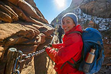 Young woman hiking on the via ferrata of the Angels Landing Trail, in winter, Zion Canyon, mountain landscape, Zion National Park, Utah, USA, North America