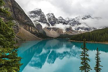 Clouds hanging between the mountain peaks, reflection in turquoise glacial lake, Moraine Lake, Valley of the Ten Peaks, Rocky Mountains, Banff National Park, Alberta Province, Canada, North America