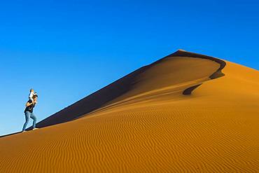 Woman with her baby walking up the giant sanddune Dune 45, Namib-Naukluft National Park, Namibia, Africa