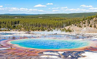 Visitors on footbridge over steaming hot spring with coloured mineral deposits, Grand Prismatic Spring, Midway Geyser Basin, Yellowstone National Park, Wyoming, USA, North America