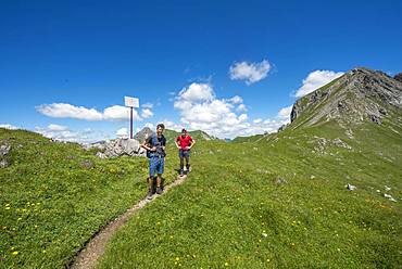 Two hikers on hiking trail Jubilaeumsweg at the Kirchdachsattel, sign state border, Allgaeuer Alps, Allgaeu, Bavaria, Germany, Europe