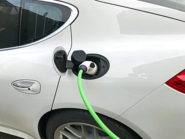 Charging plug on electric car, car being charged at charging station, Germany, Europe