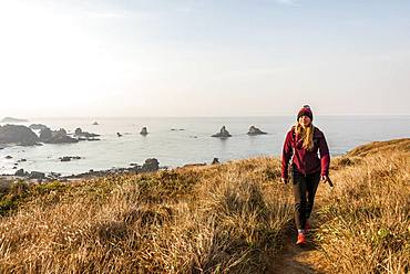 Young woman on a hiking trail along the rugged coast with many rocks, Whaleshead, Samuel H. Boardman State Scenic Corridor, Oregon, USA, North America