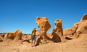 Tourist, young man next to eroded Hoodoos, rock formation of Entrada sandstone, Goblin Valley State Park, San Rafael Reef, Utah, Southwest, USA, North America