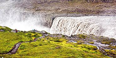 Hikers at the edge of the Dettifoss waterfall with falling water masses, North Iceland, Iceland, Europe